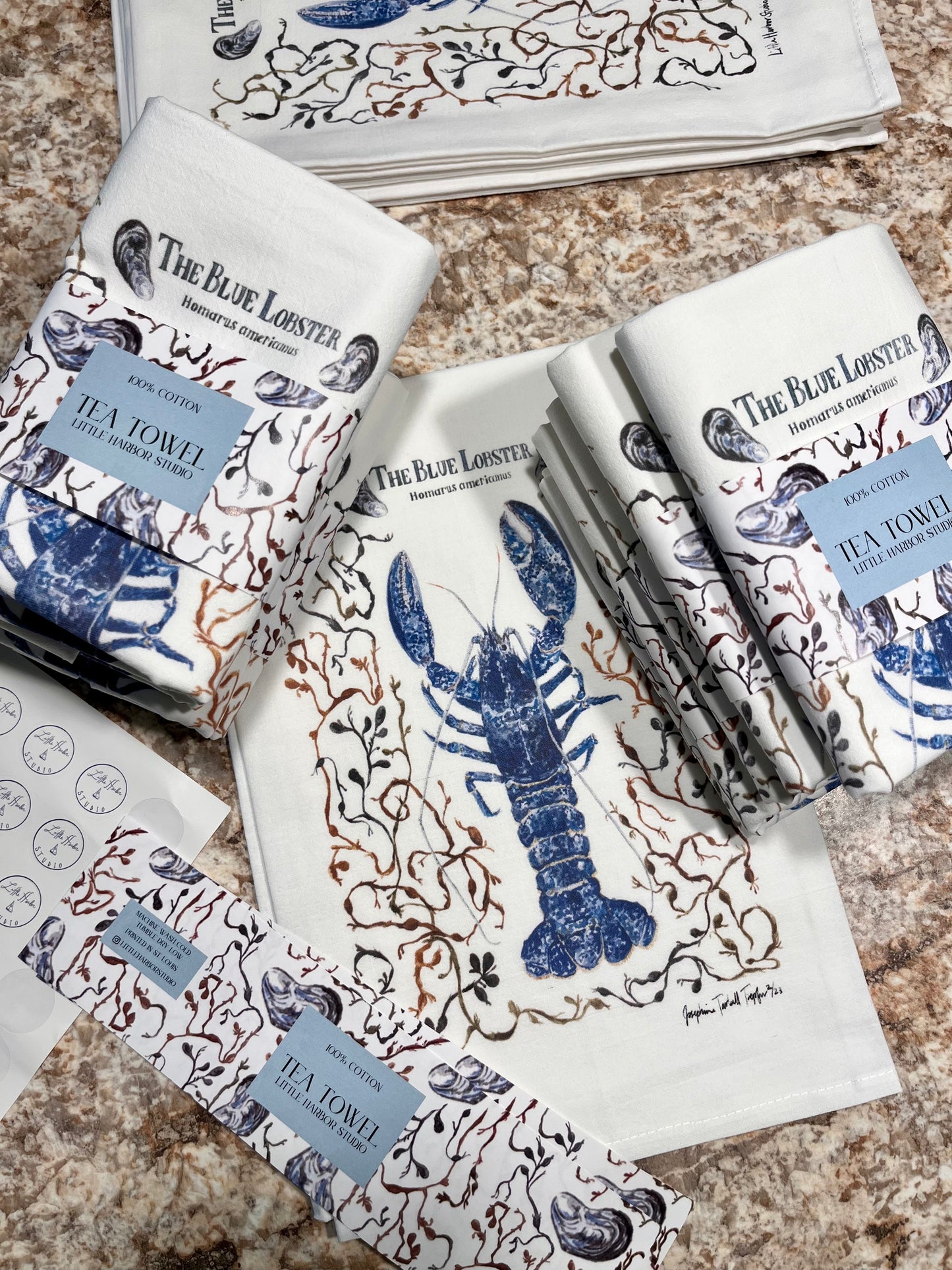 Blue lobster framed by Atlantic seaweeds and mussels hand painted on a cotton tea towel