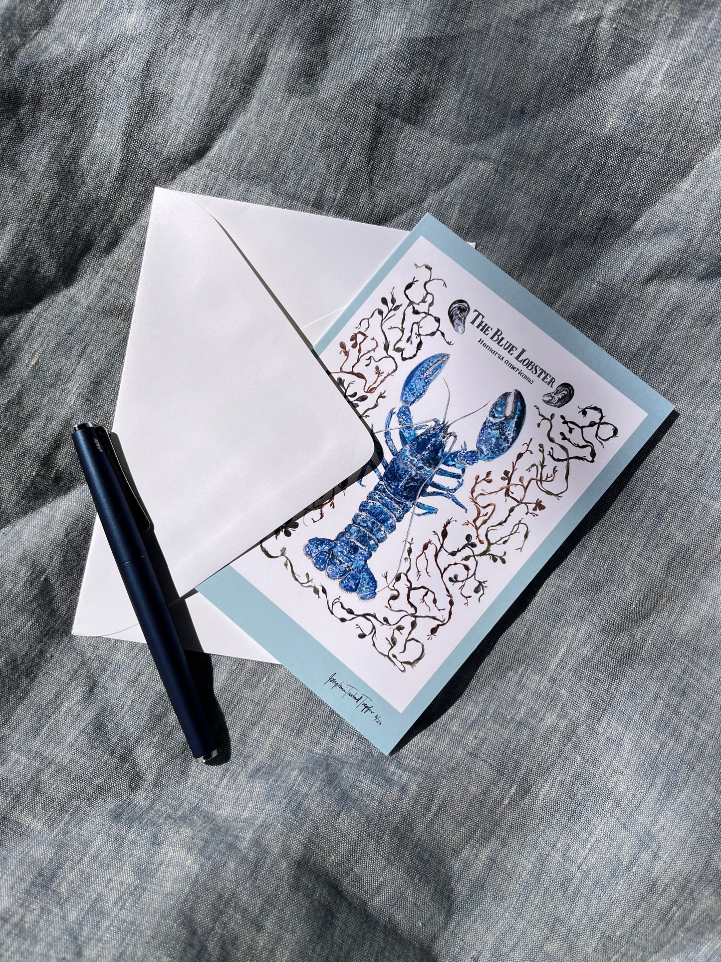 Fold over hand painted greeting card with blue lobster, seaweed, and clams.